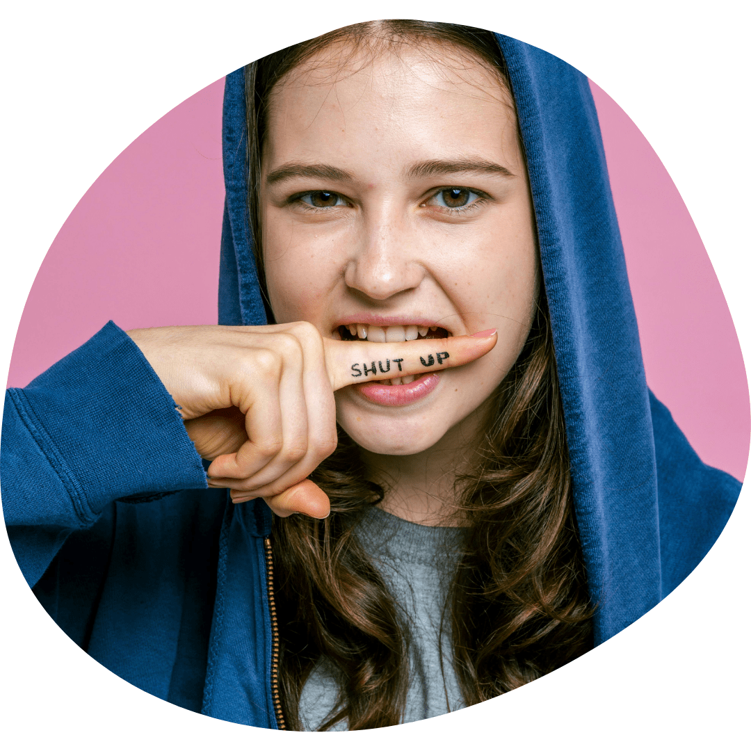 Teen girl with "shut up" tattoo on finger, symbolizing silenced voice — raising awareness of harmful trainer behaviour in riding lessons.